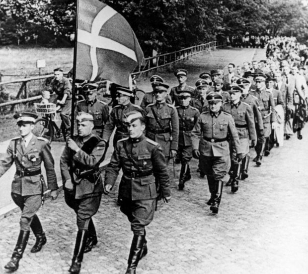 Voluntarios del Cuerpo SS Libre Danés en formación con la bandera de Dinamarca.